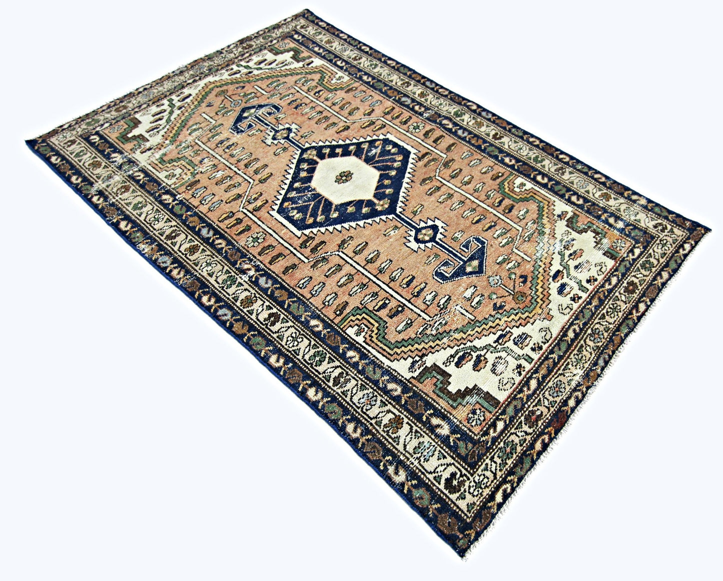 A vintage handmade Persian rug featuring a central geometric medallion on a muted peach field.