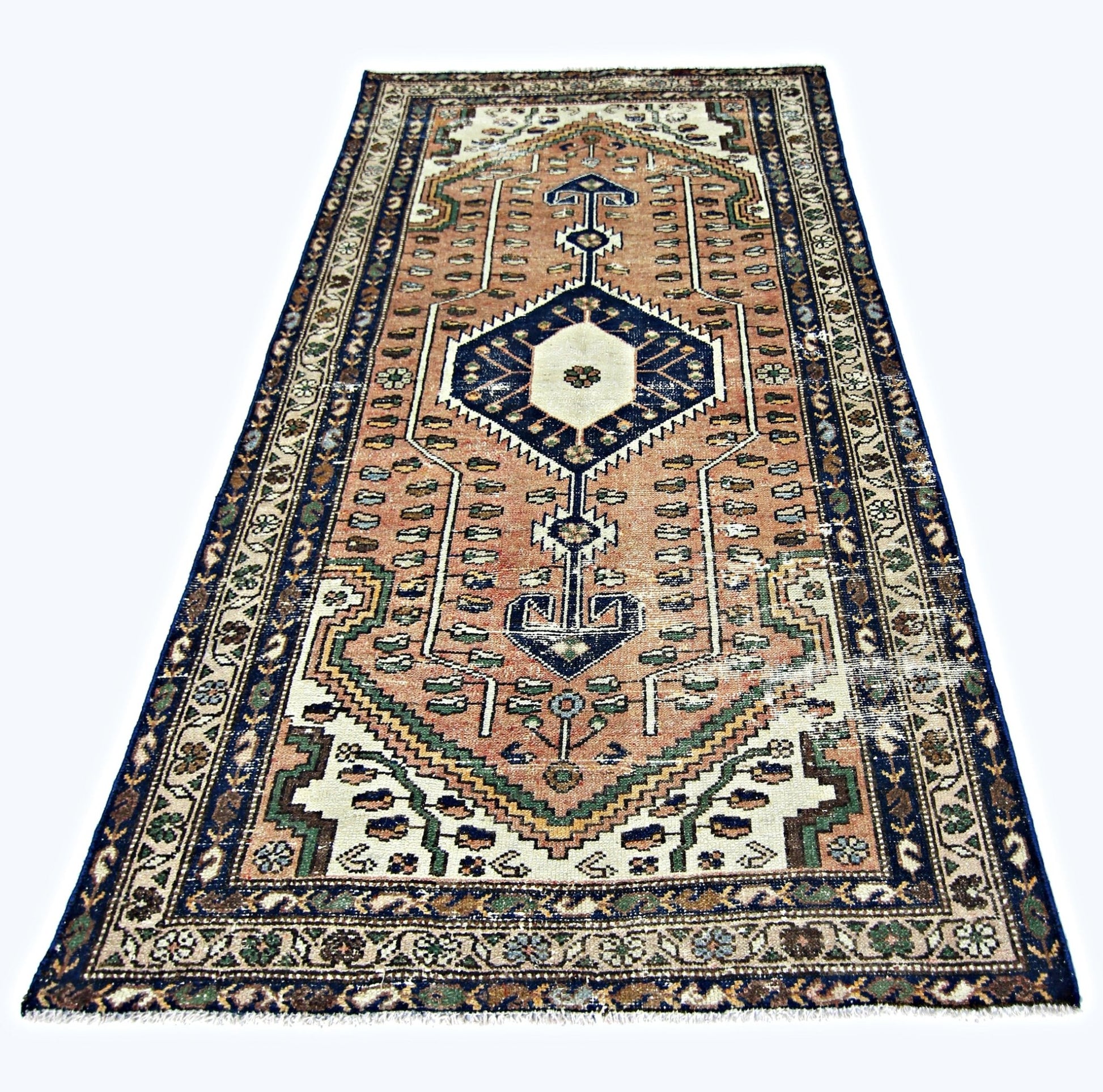 A vintage handmade Persian rug featuring a geometric medallion pattern in peach, blue, and cream.