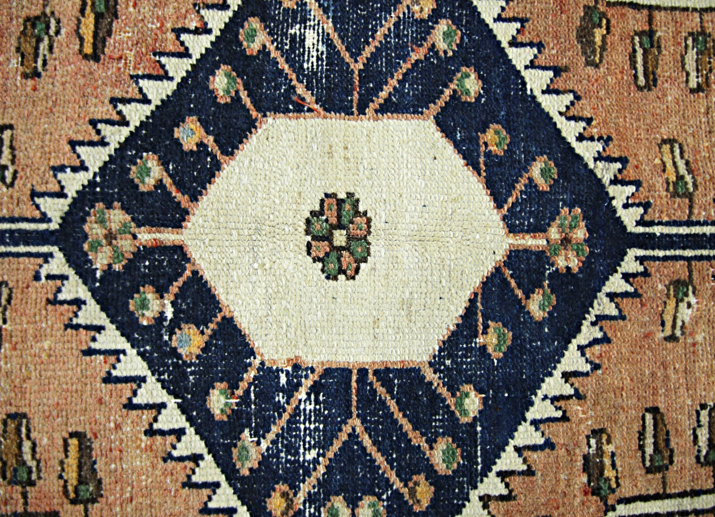 A vintage Persian rug featuring a central white hexagon with floral motifs on a dark blue field.
