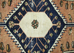 A vintage Persian rug featuring a central white hexagon with floral motifs on a dark blue field.
