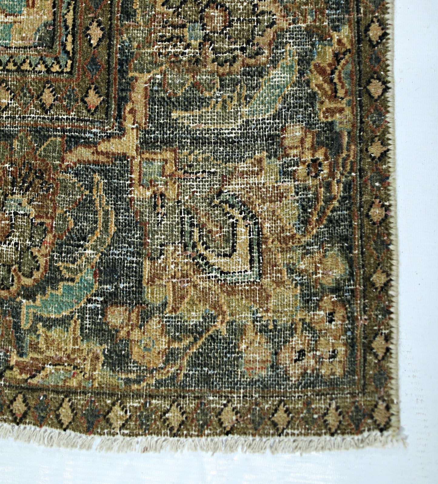 A vintage handmade Persian rug featuring intricate floral patterns in muted green and tan tones.
