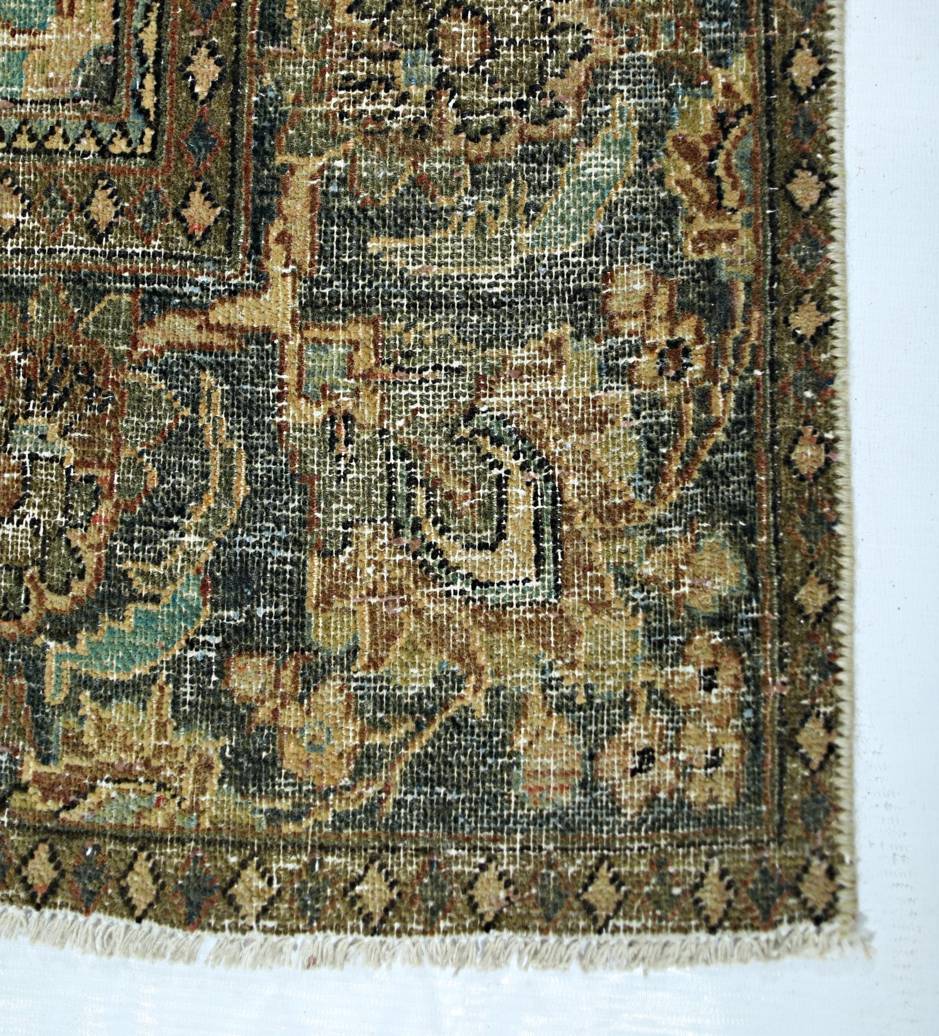 A vintage handmade Persian rug featuring intricate floral patterns in muted green and tan tones.