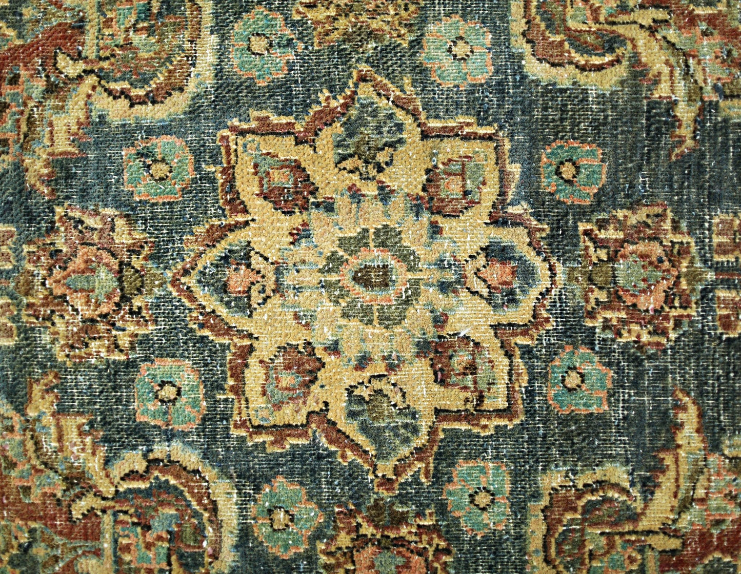 A vintage Persian rug featuring a central floral medallion in muted tones on a dark background.