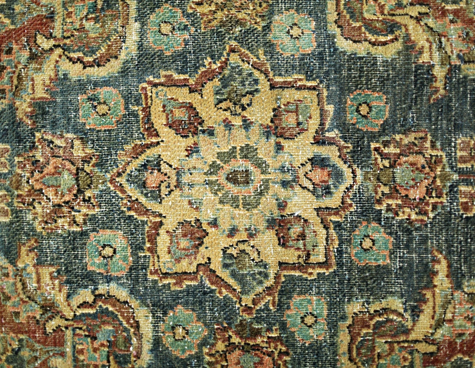 A vintage Persian rug featuring a central floral medallion in muted tones on a dark background.