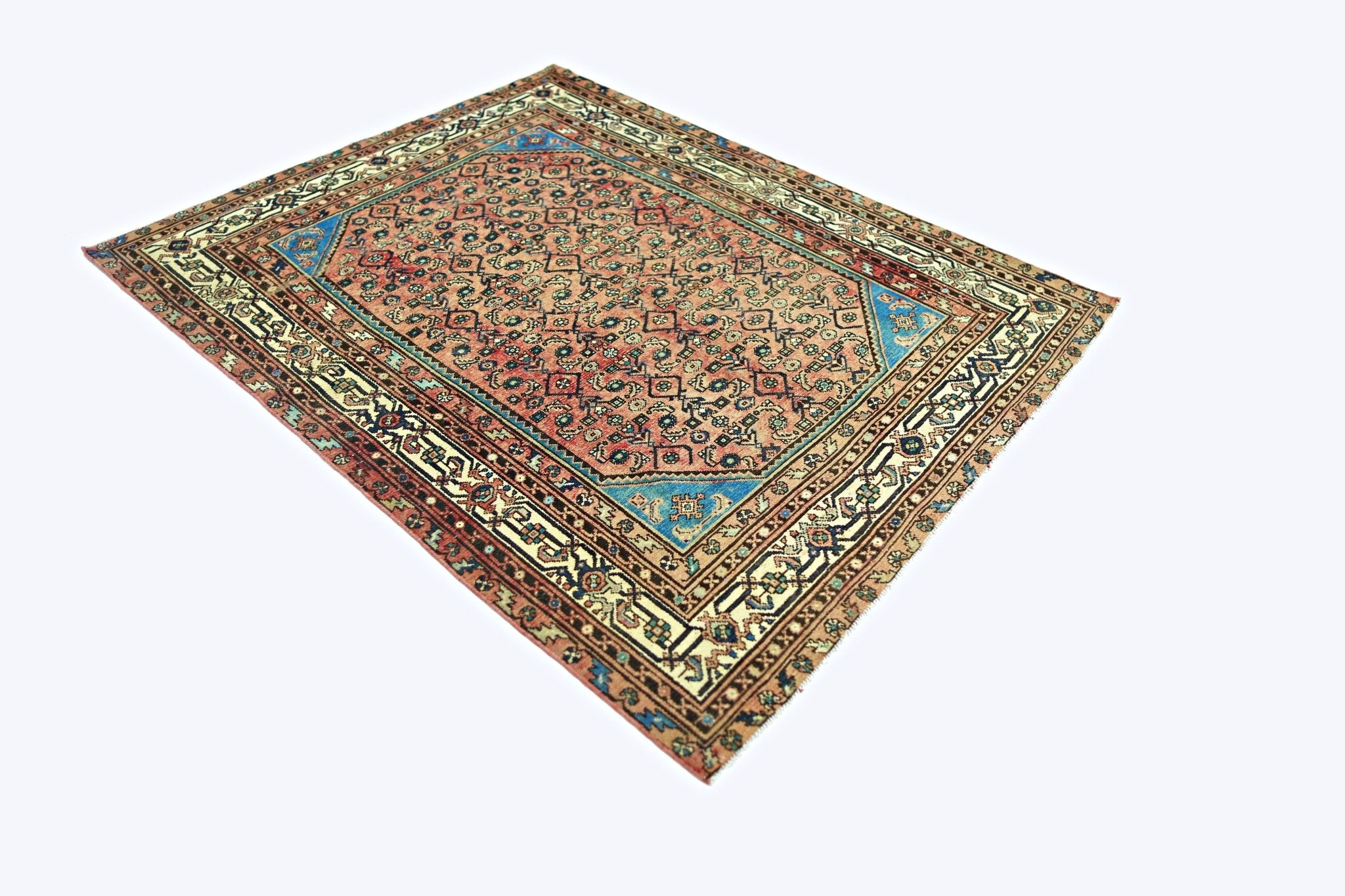 A vintage handmade Persian rug featuring a geometric floral pattern in red, blue, and cream tones.