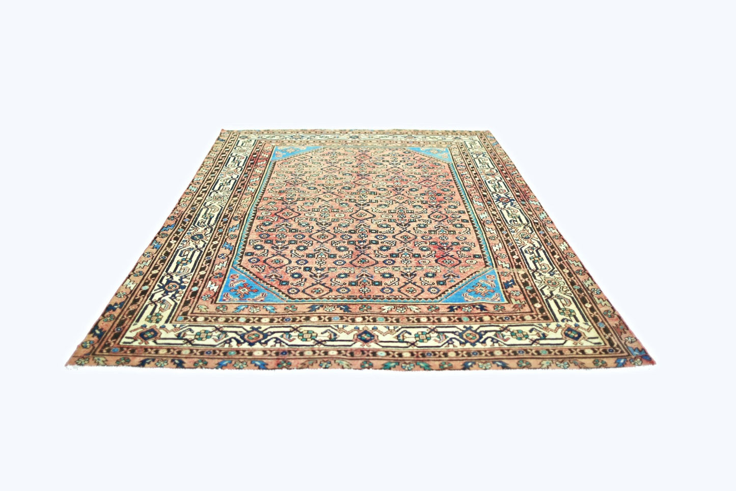 A vintage handmade Persian rug featuring a geometric floral pattern in pink and blue tones.