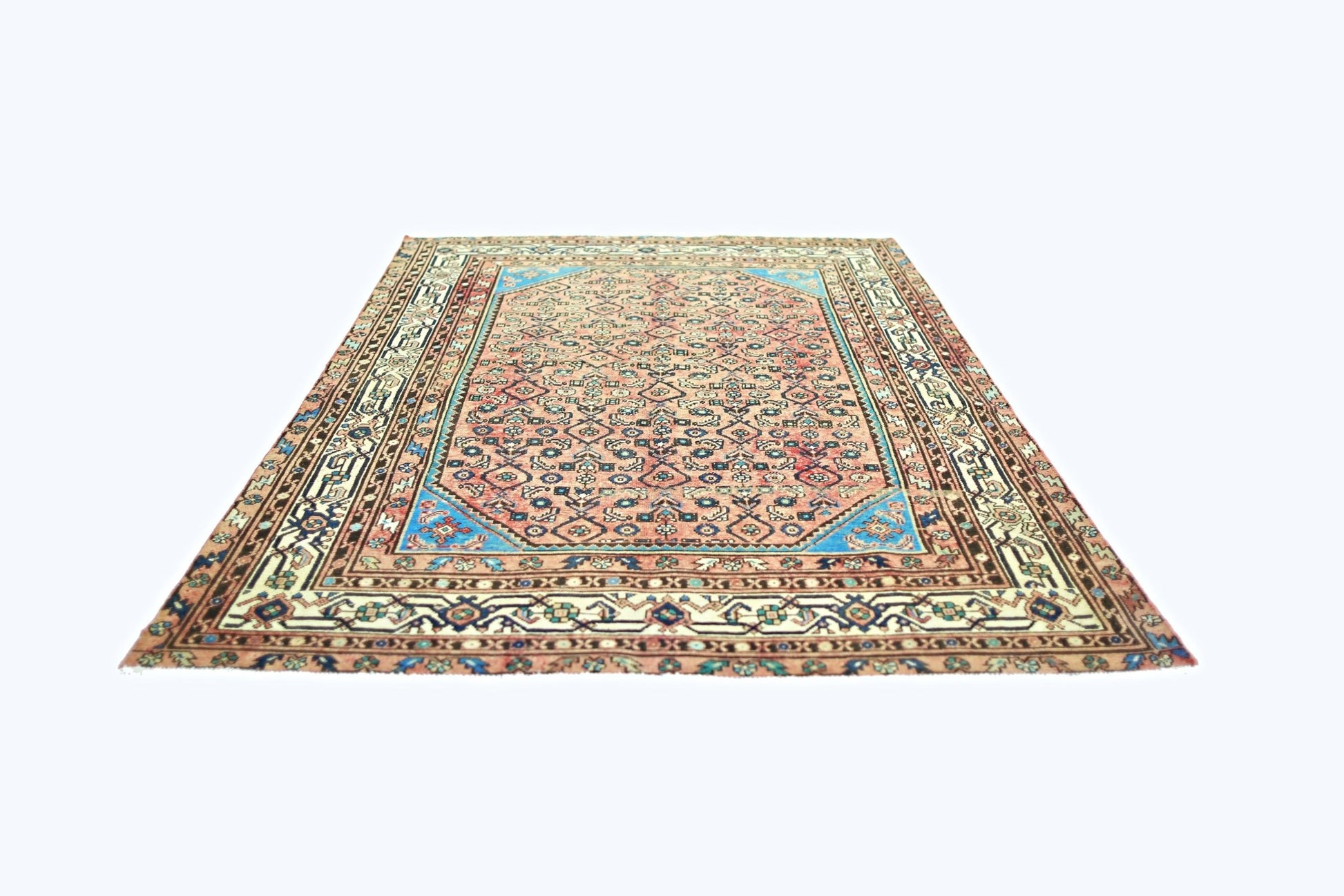 A vintage handmade Persian rug featuring a geometric floral pattern in pink and blue tones.