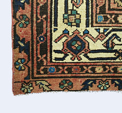 A corner view of a vintage Persian rug featuring intricate geometric patterns in red and blue.