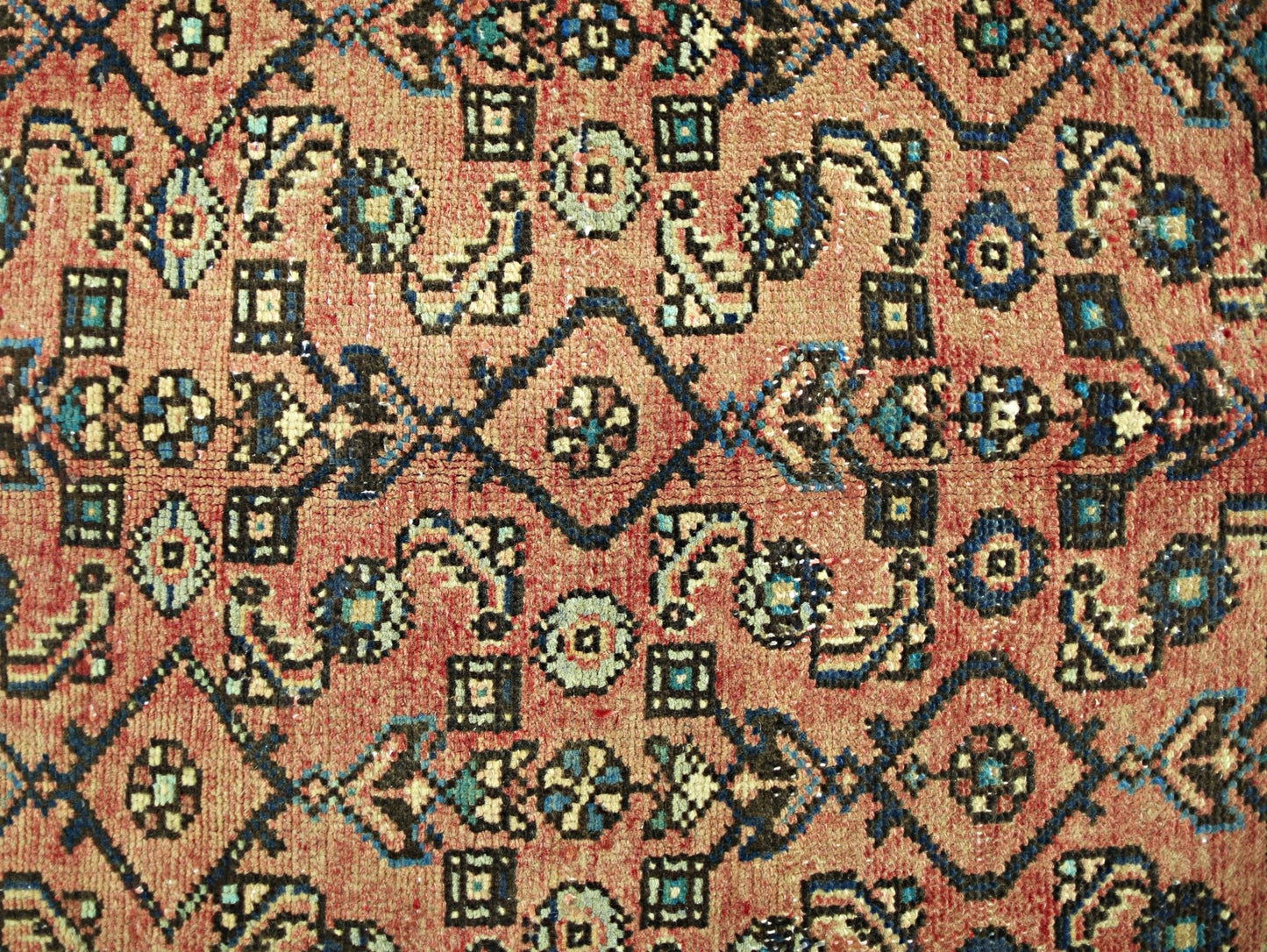 A vintage Persian rug featuring a geometric pattern in shades of red, blue, and cream.