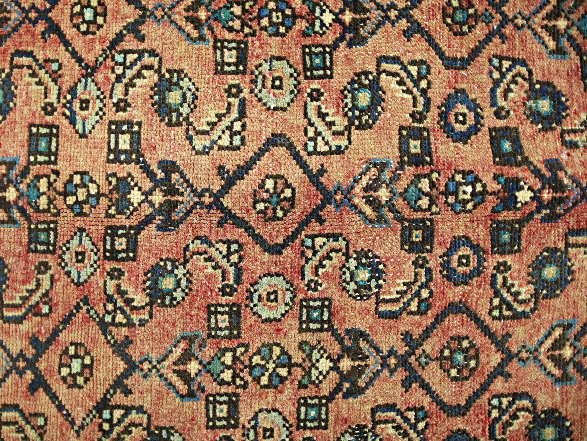 A vintage Persian rug featuring a geometric pattern in shades of red, blue, and cream.
