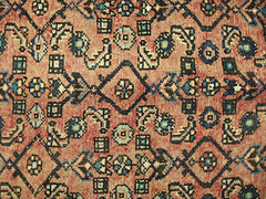 A vintage Persian rug featuring a geometric pattern in shades of red, blue, and cream.
