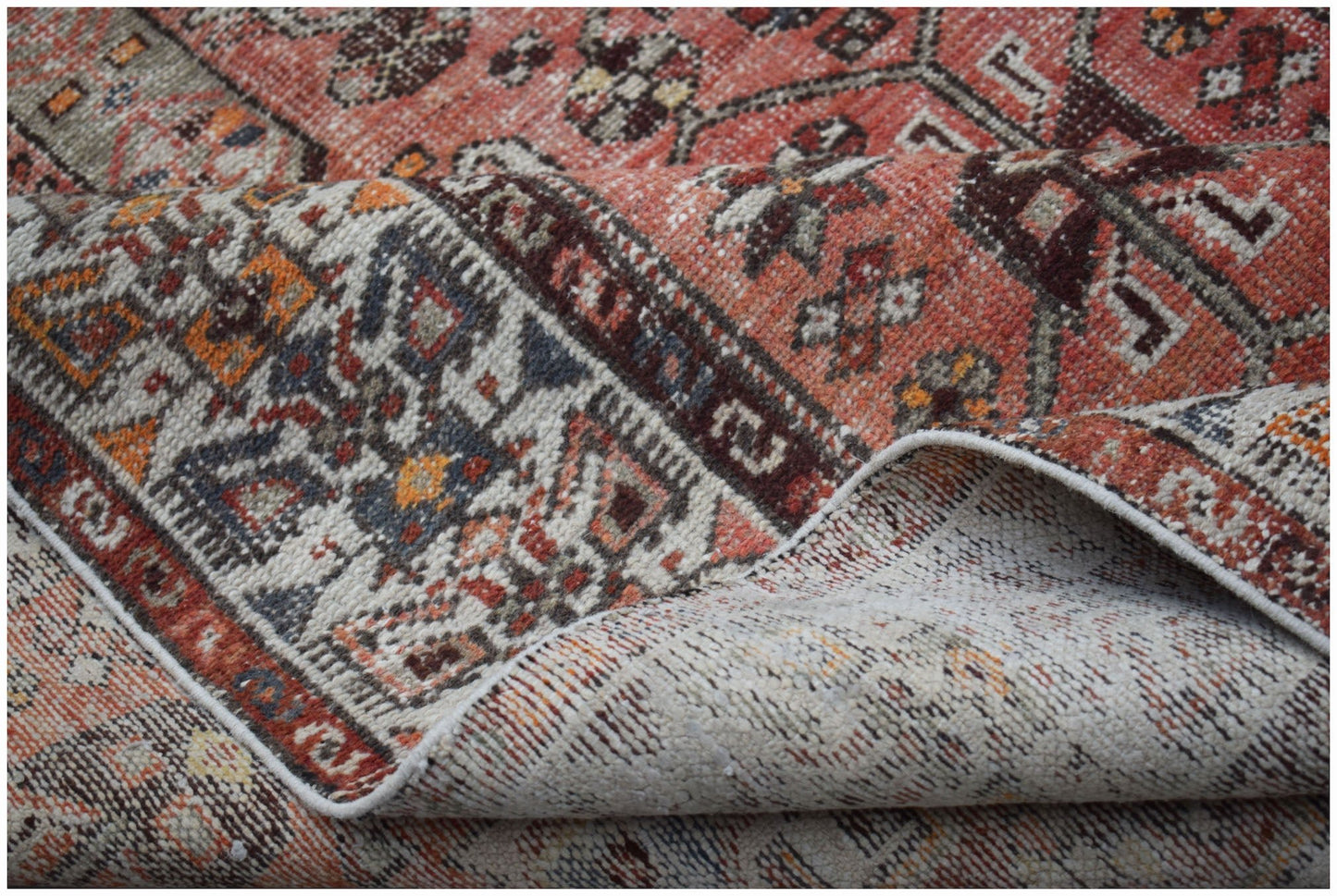 A handwoven vintage Persian rug featuring intricate geometric patterns in red, blue, and cream.