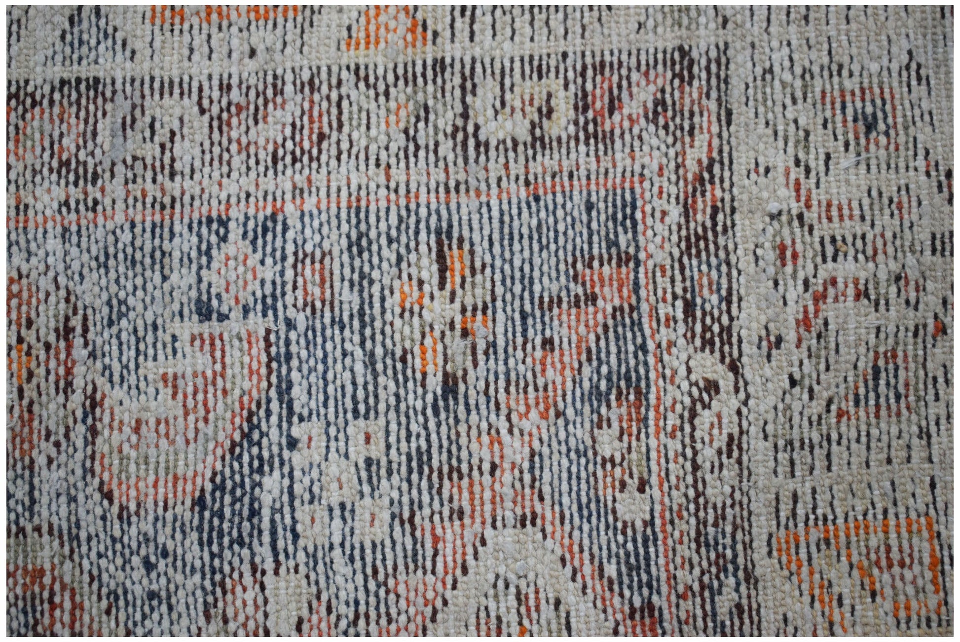 A close-up of a handwoven vintage Persian rug featuring a faded geometric pattern in wool.