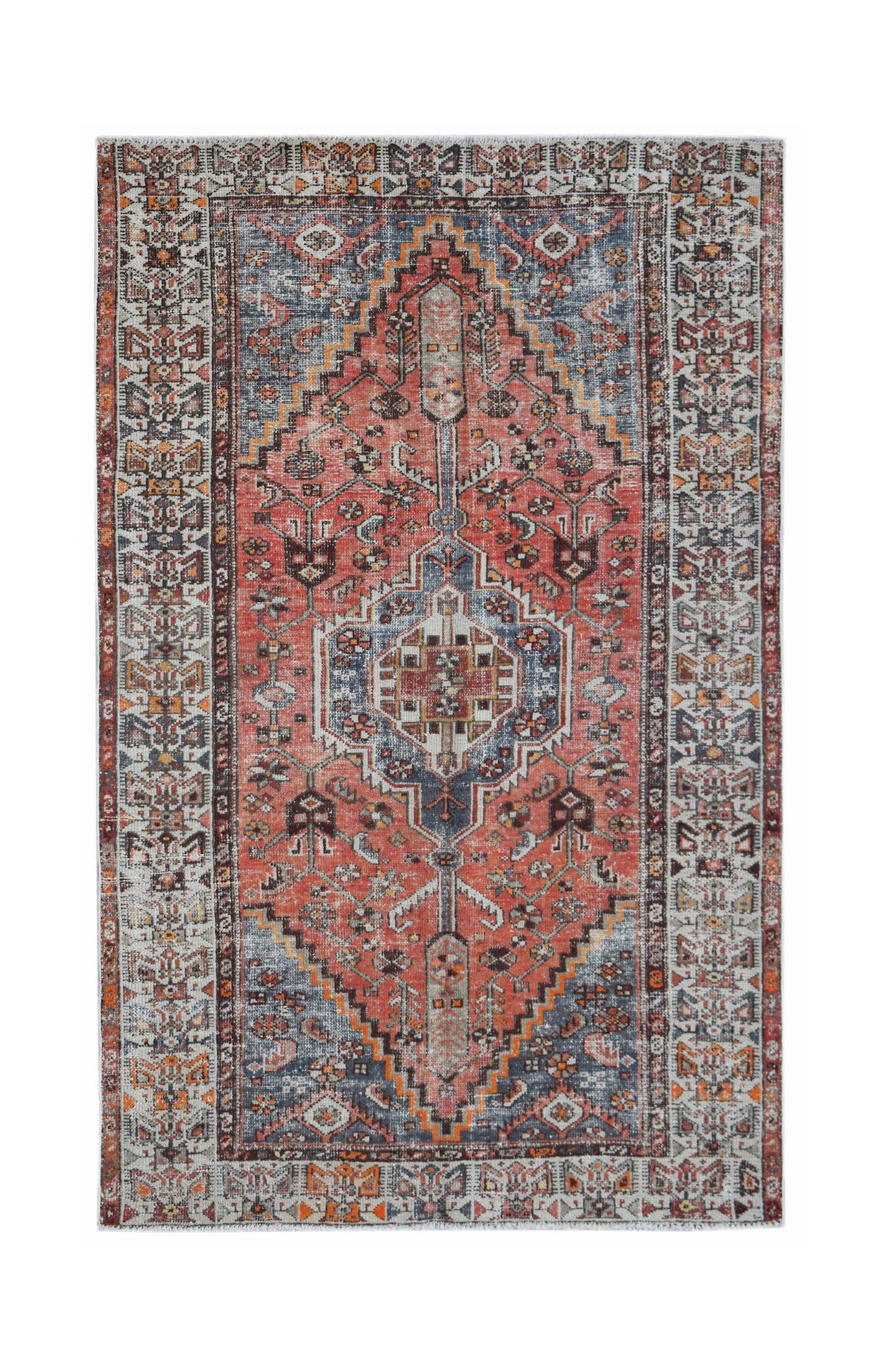A vintage Persian rug featuring a central medallion in shades of red, blue, and cream.
