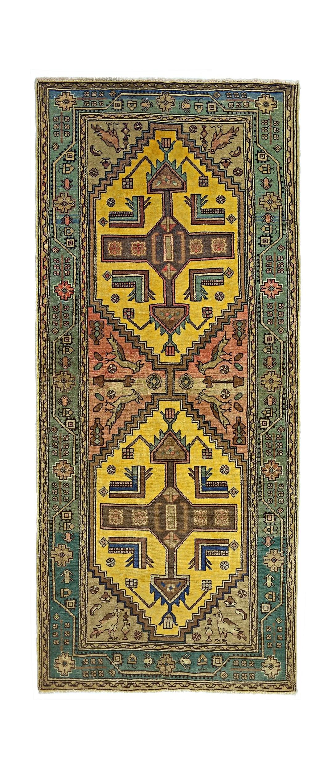 A handmade vintage Persian rug featuring geometric yellow medallions and bird motifs on a green border.