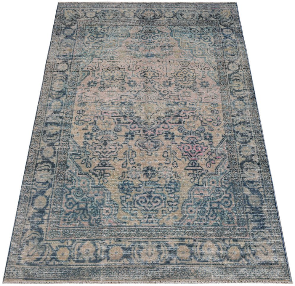 A vintage Turkish rug featuring a faded floral medallion pattern in shades of blue and pink.