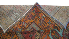 A folded vintage Persian rug featuring intricate geometric patterns in orange, blue, and red.