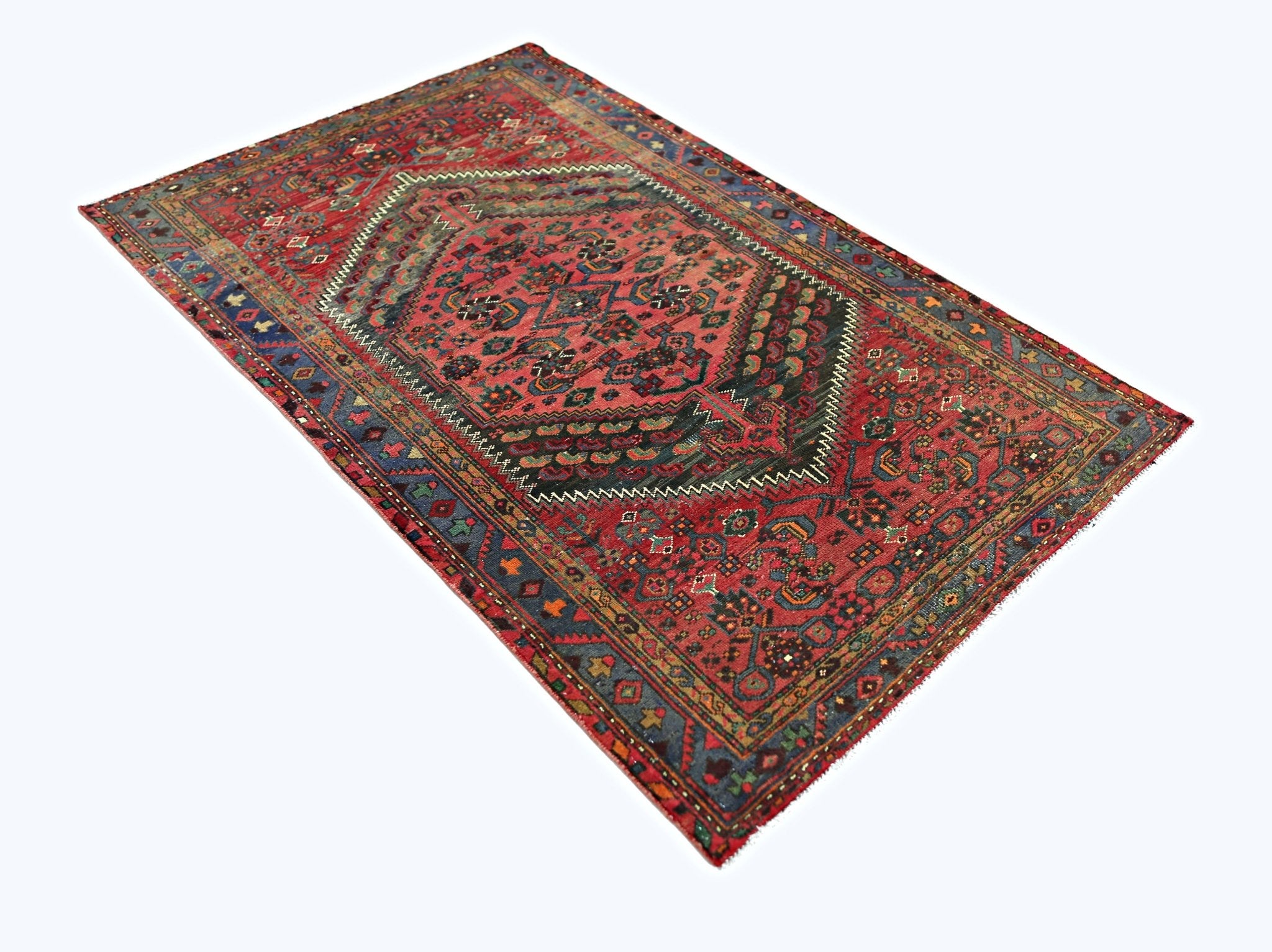 A vintage Persian rug featuring a central geometric medallion on a red field with blue borders.
