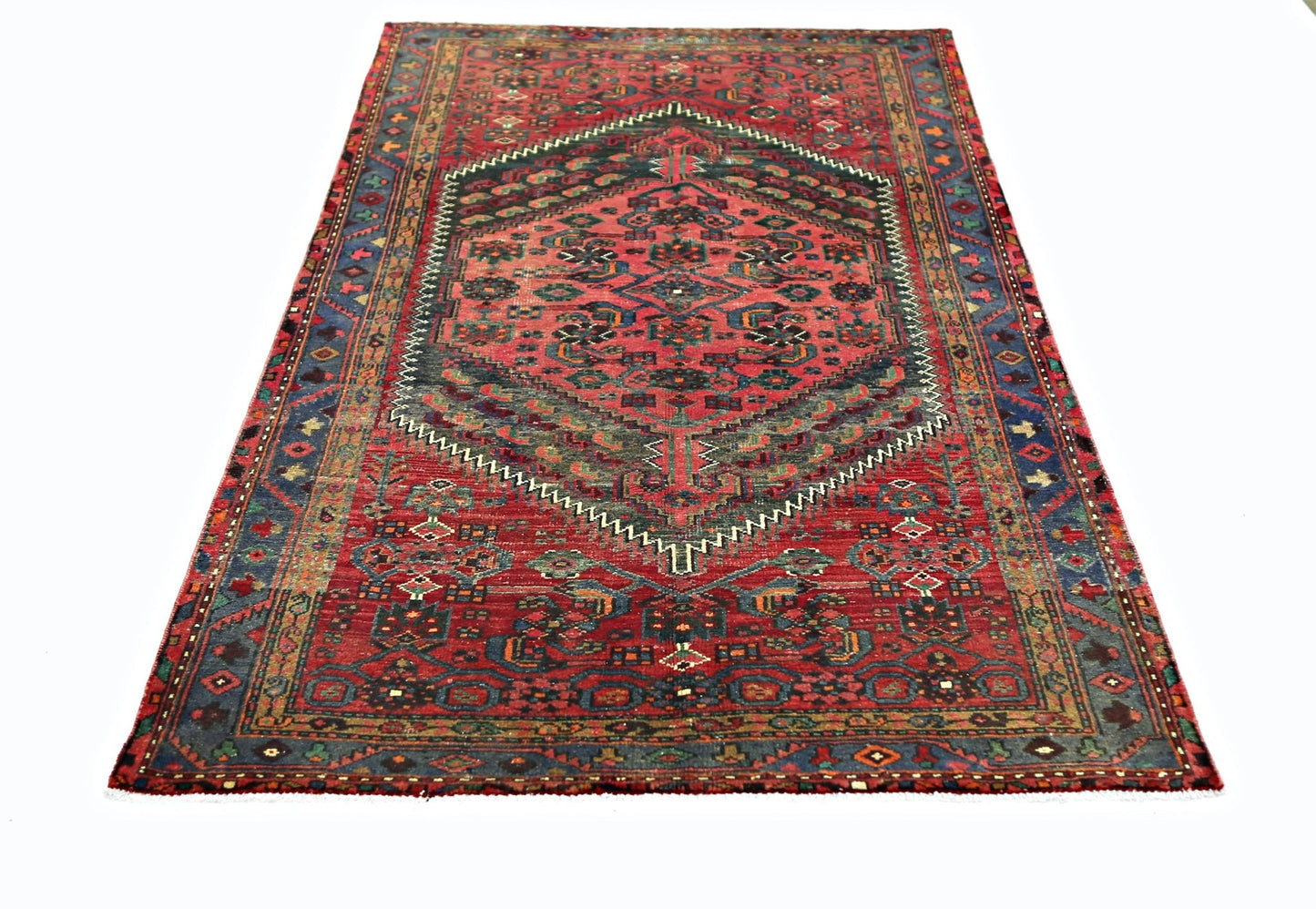 A vintage Persian rug featuring a central geometric medallion on a red field with blue borders.