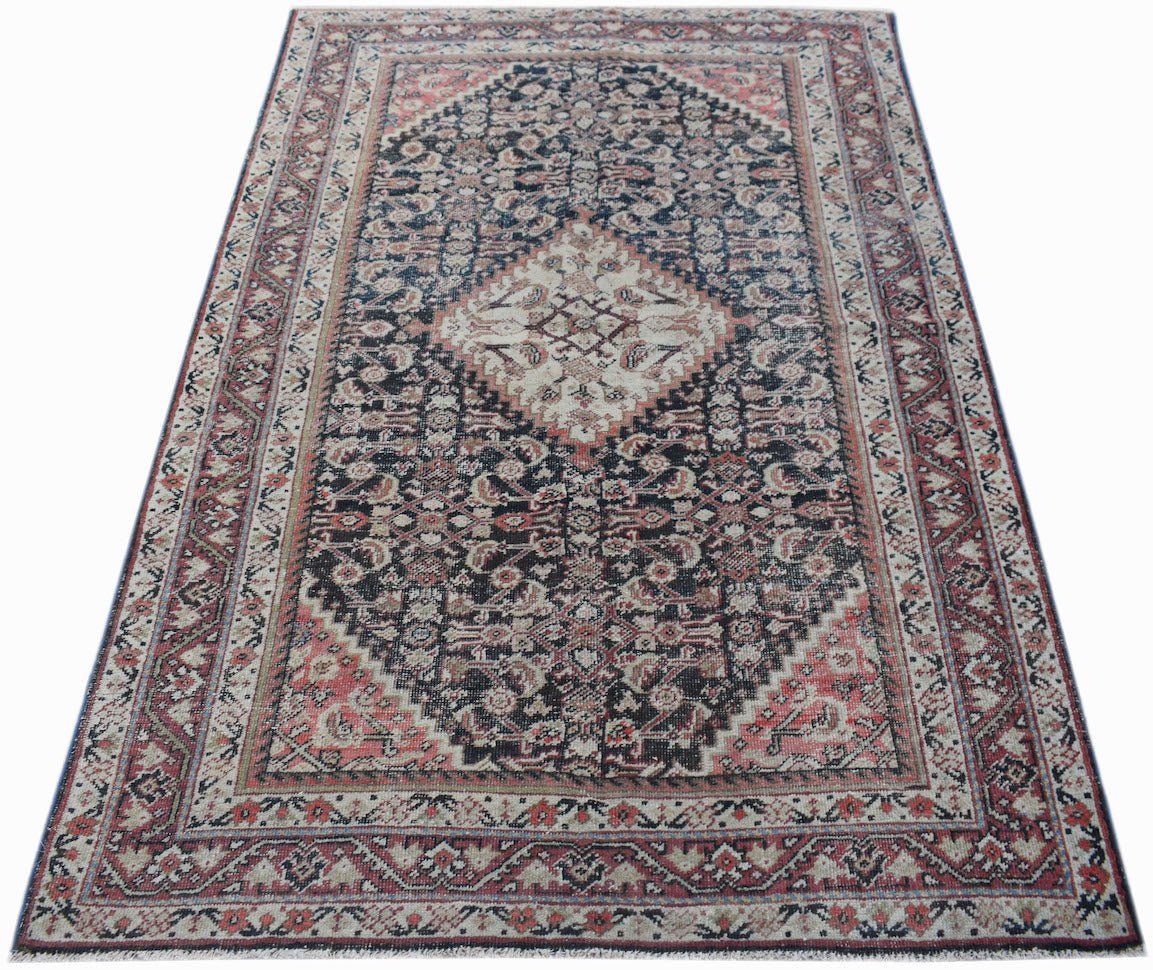 A handwoven vintage Persian rug featuring a central diamond medallion on a dark patterned field.