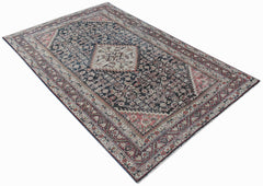 A vintage handwoven Persian rug featuring a dark central medallion and intricate floral patterns.