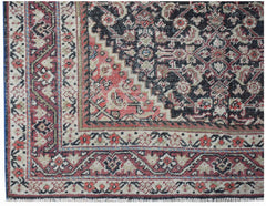 A vintage handwoven Persian rug featuring a geometric pattern in red, black, and cream tones.
