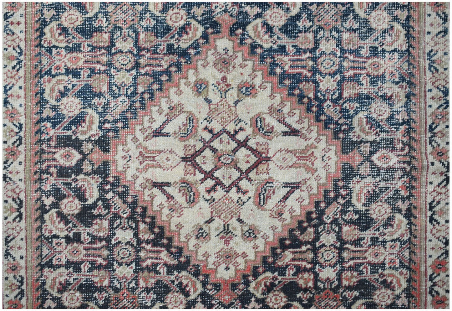A vintage handwoven Persian rug featuring a central diamond medallion in cream, blue, and red.