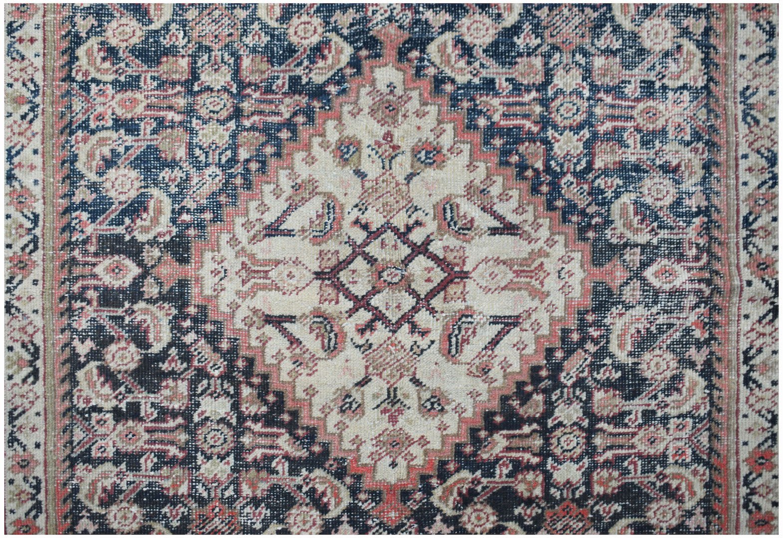 A vintage handwoven Persian rug featuring a central diamond medallion in cream, blue, and red.