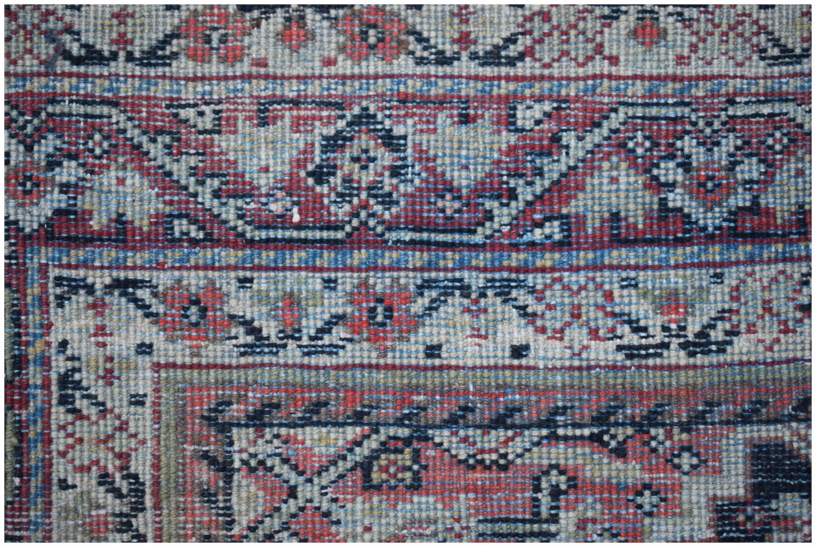 A close-up of a vintage handwoven Persian rug featuring intricate geometric and floral patterns.