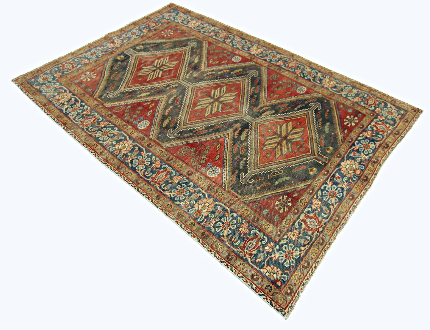 A vintage handmade Persian rug featuring three central diamond medallions on a red field.