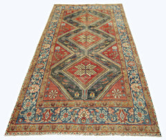 A vintage handmade Persian rug featuring three large diamond medallions on a red and grey field.
