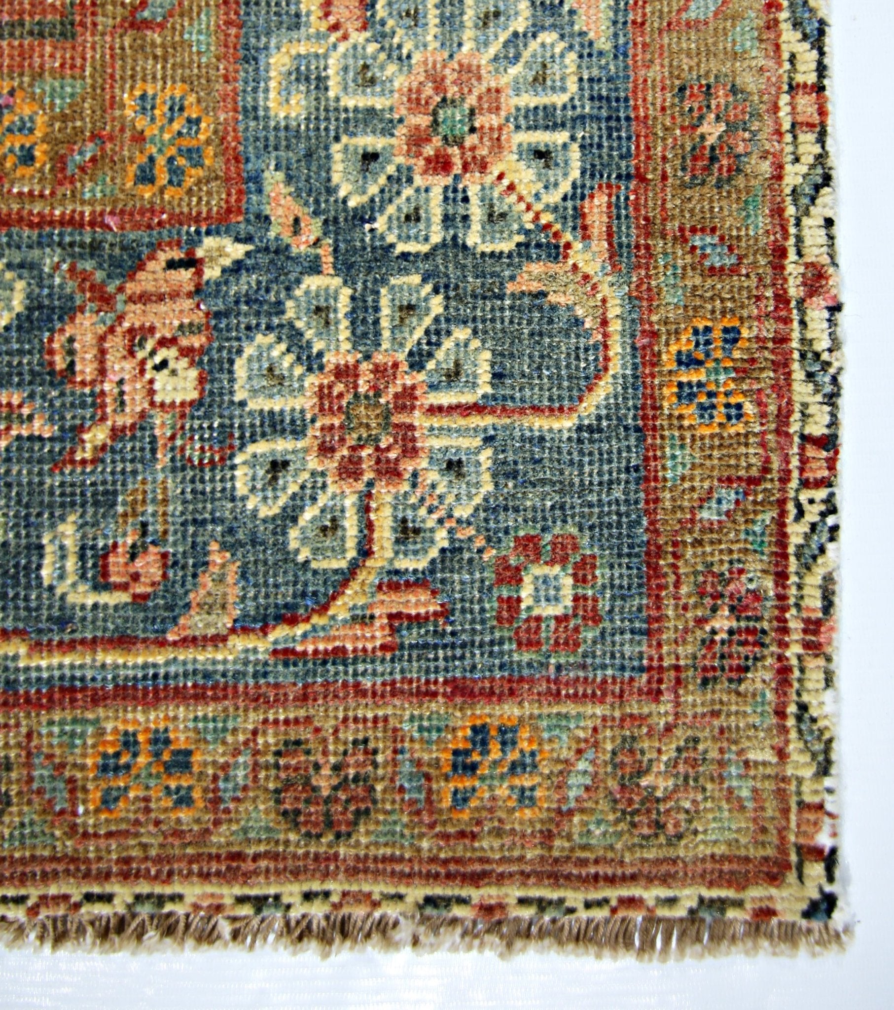 A vintage Persian rug featuring a blue field with floral patterns and a tan border.
