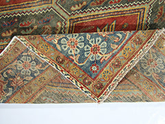 A vintage handmade Persian rug with intricate floral patterns in red, blue, and tan tones.