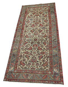 A vintage handmade Persian runner rug featuring a floral pattern in red, blue, and cream tones.