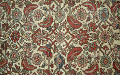 A vintage Persian rug featuring a detailed floral pattern in shades of red, green, and cream.