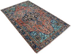 A rectangular vintage Persian rug featuring a central medallion on a salmon and blue floral field.