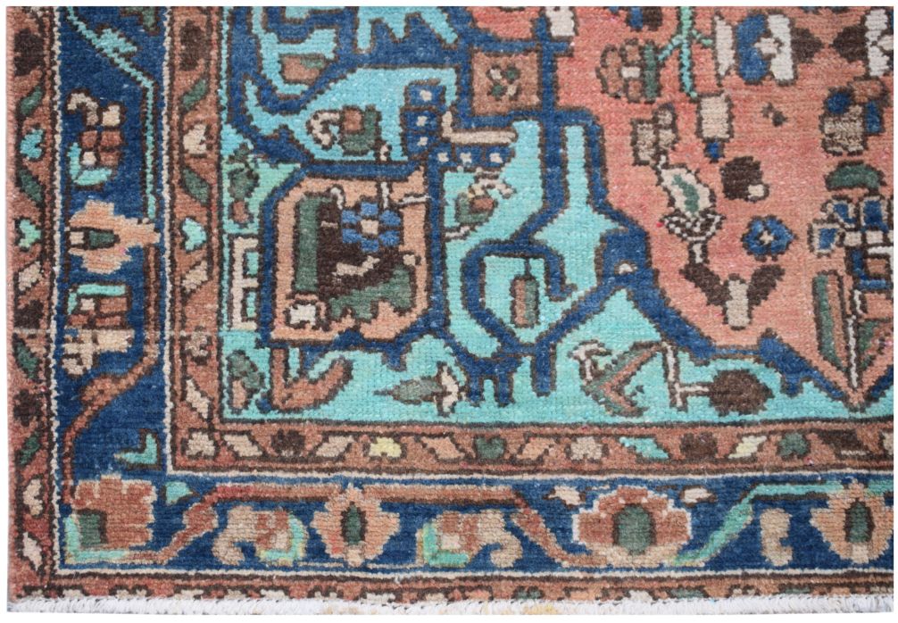 A vintage Persian rug featuring a geometric floral pattern in shades of blue, pink, and brown.