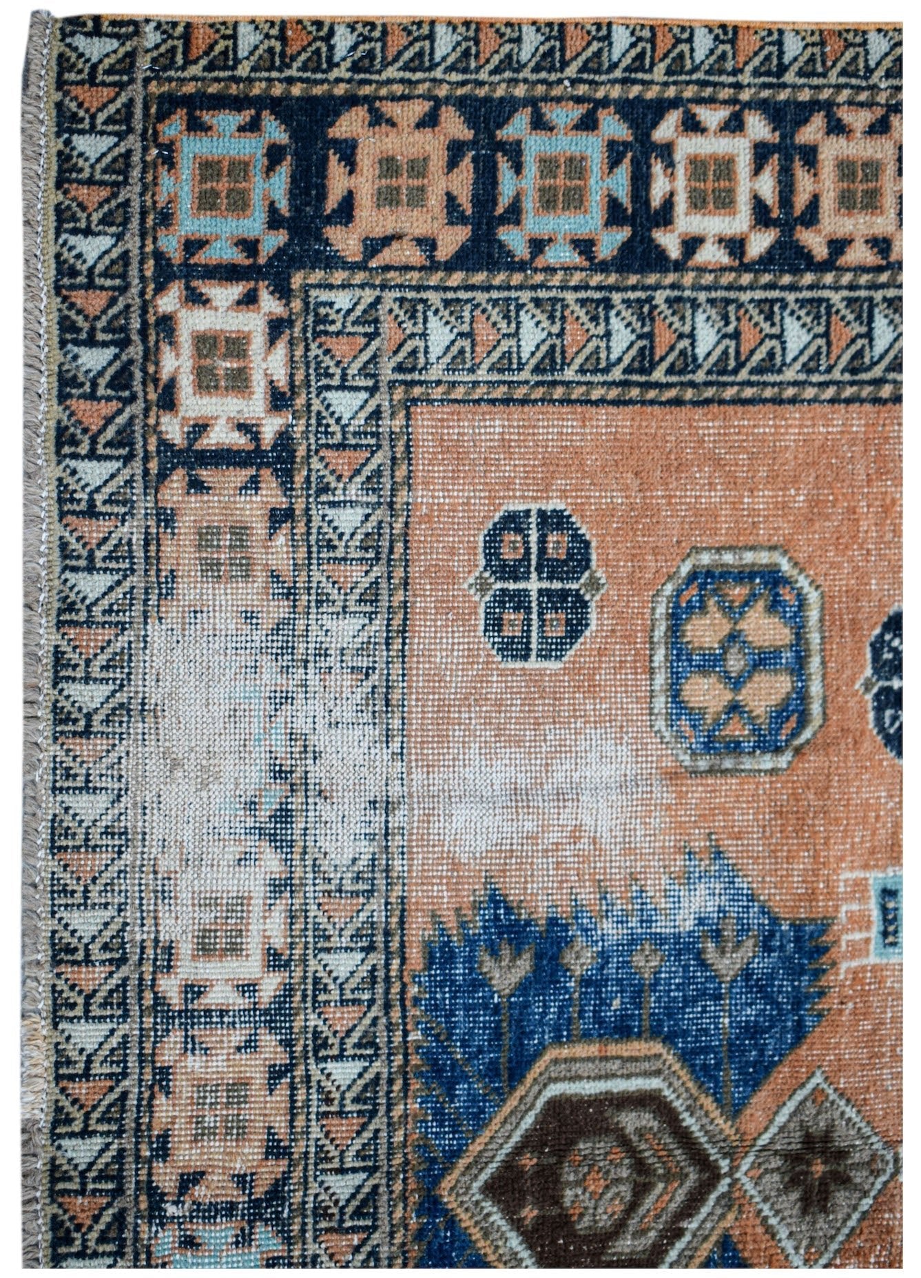 A vintage handwoven Persian rug featuring geometric patterns in orange, blue, and cream tones.