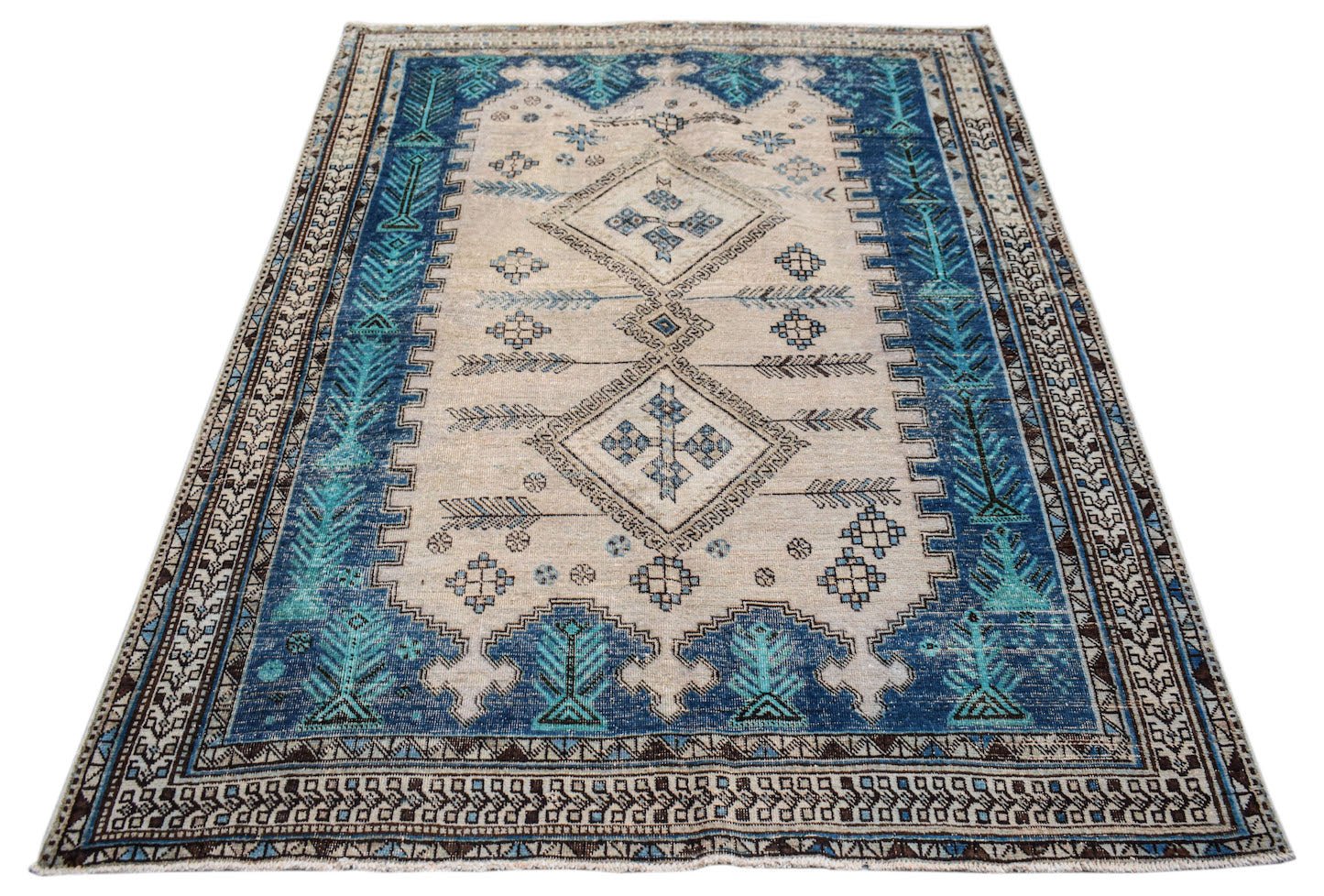 A vintage handwoven Persian rug featuring a cream field with blue geometric diamond motifs.