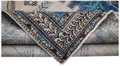 A handwoven vintage Persian rug featuring a geometric pattern in blue, brown, and cream tones.