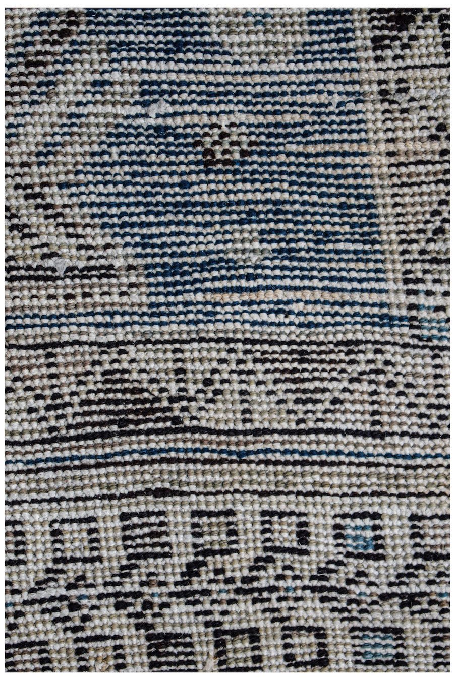 A close-up view of a handwoven vintage Persian rug featuring geometric patterns in blue and beige.