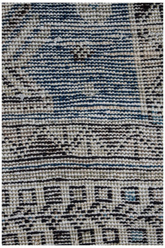 A close-up view of a handwoven vintage Persian rug featuring geometric patterns in blue and beige.