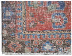 A vintage handwoven Persian rug featuring a floral pattern in red, blue, and brown tones.