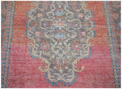 A vintage handwoven Persian rug featuring a central floral medallion on a faded red background.