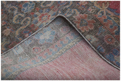 A corner of a vintage handwoven Persian rug showing its worn wool pile and cotton foundation.