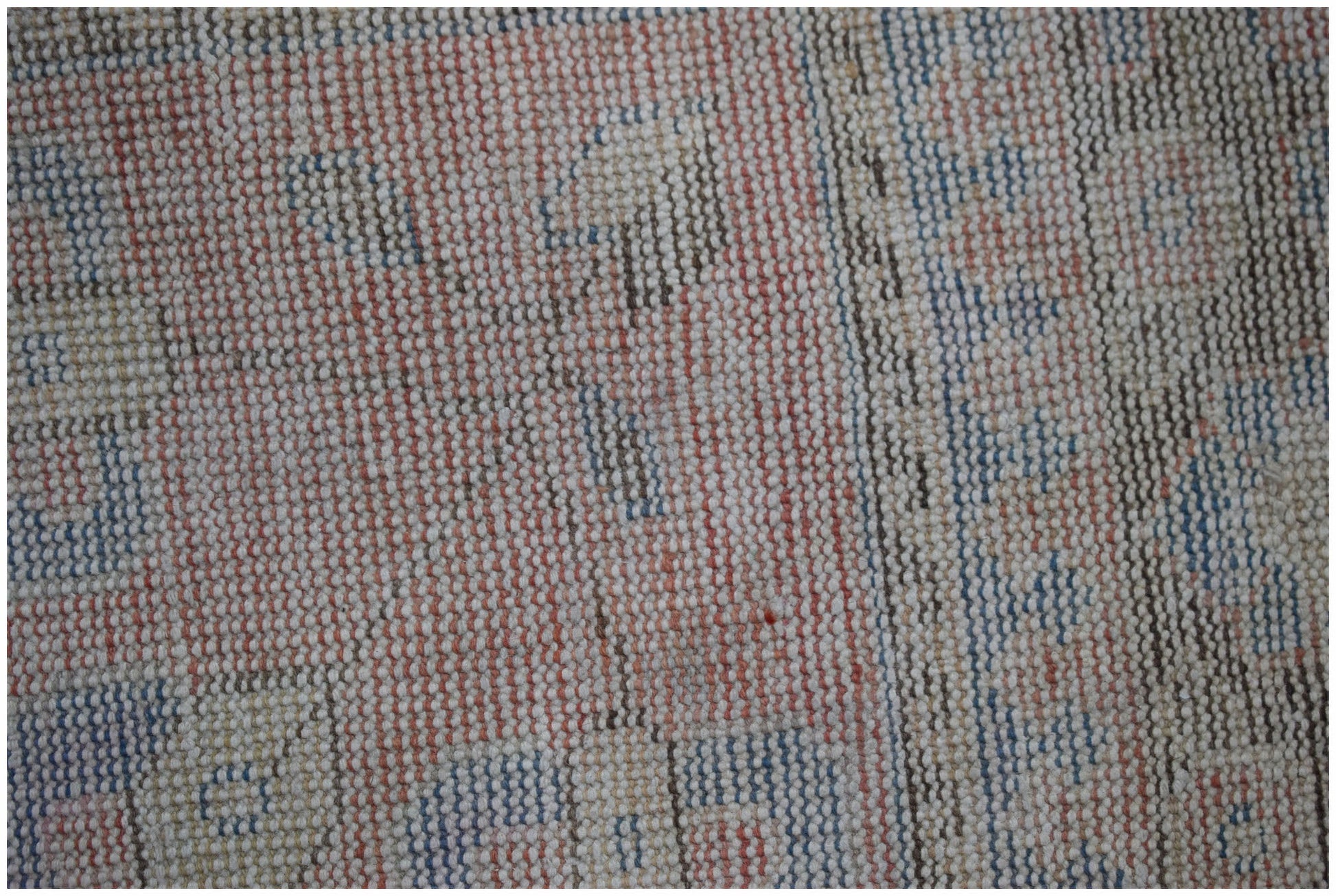 A close-up view of a handwoven vintage Persian rug featuring a faded geometric pattern in wool.