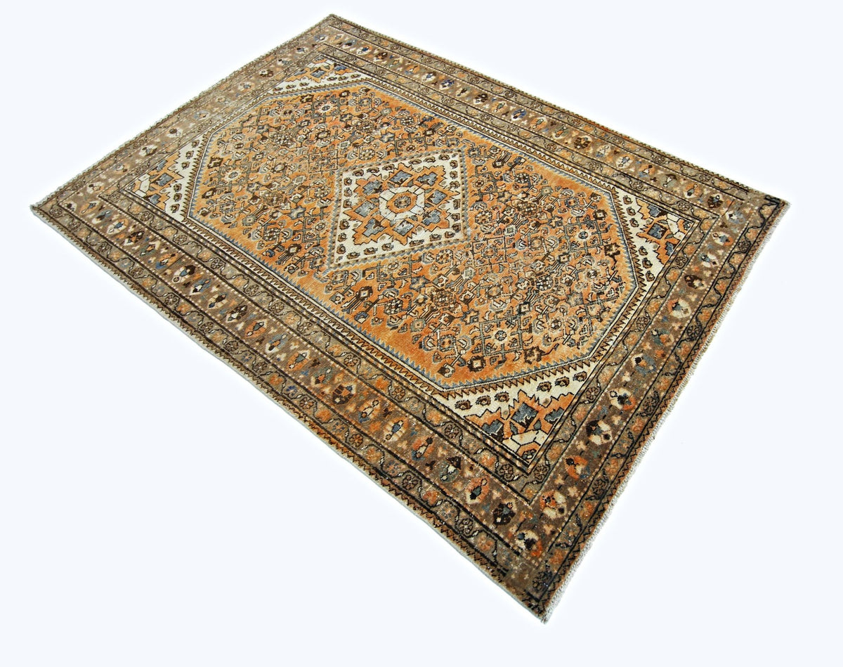 A vintage Persian rug featuring an intricate orange and brown geometric pattern on a white background.
