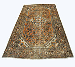 A vintage handmade Persian rug featuring an intricate orange and blue geometric pattern.