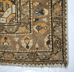 A vintage Persian rug featuring a geometric floral pattern in muted brown, blue, and orange tones.