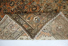A vintage Persian rug with a folded corner revealing its intricate floral pattern and wool texture.